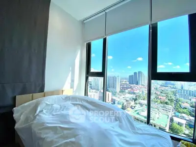 Bright bedroom with stunning city view from large windows, showcasing modern urban living.