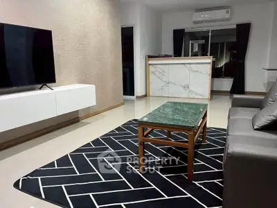 Modern living room with sleek furniture and stylish decor, featuring a marble counter and large TV.