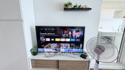 Modern living room with TV and fan, showcasing sleek storage and decor.