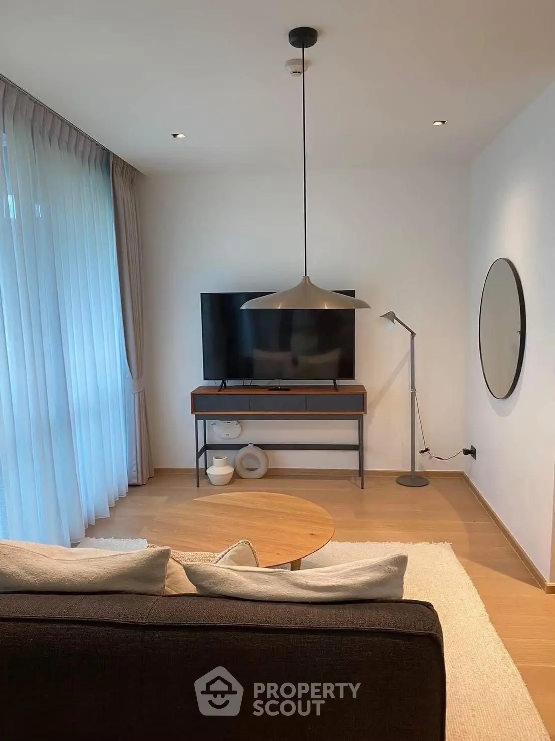 Modern living room with stylish decor, featuring a sleek TV setup and elegant lighting.