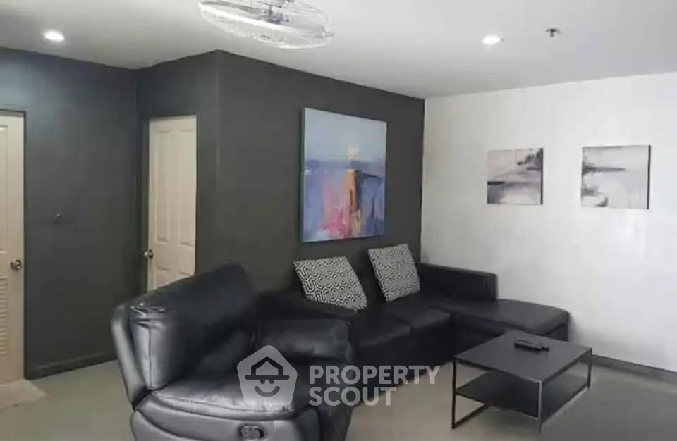 Modern living room with black leather sofa and abstract art on walls