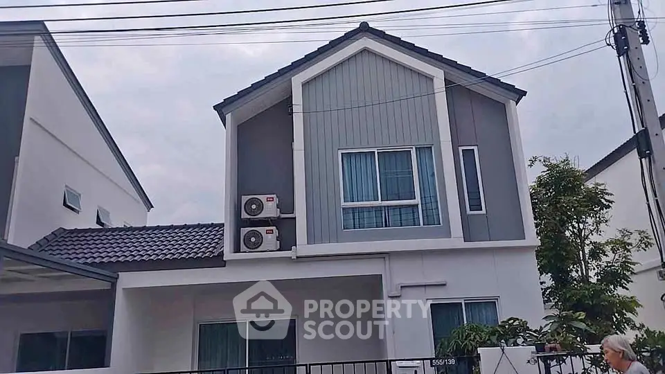 Modern two-story house with air conditioning units and contemporary design.