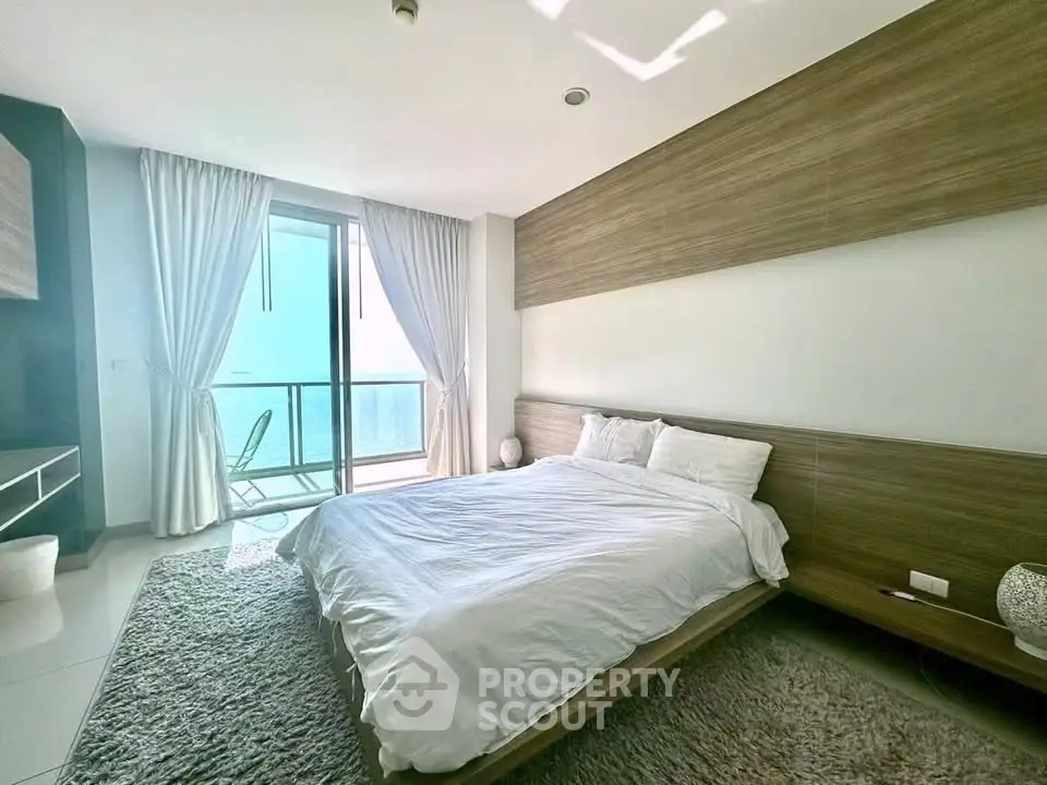 Luxurious bedroom with ocean view and modern decor in a high-rise apartment.