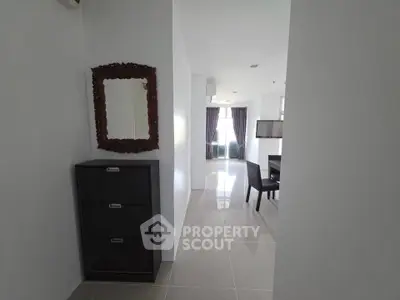 Modern apartment hallway leading to a bright living area with sleek furniture and large windows.