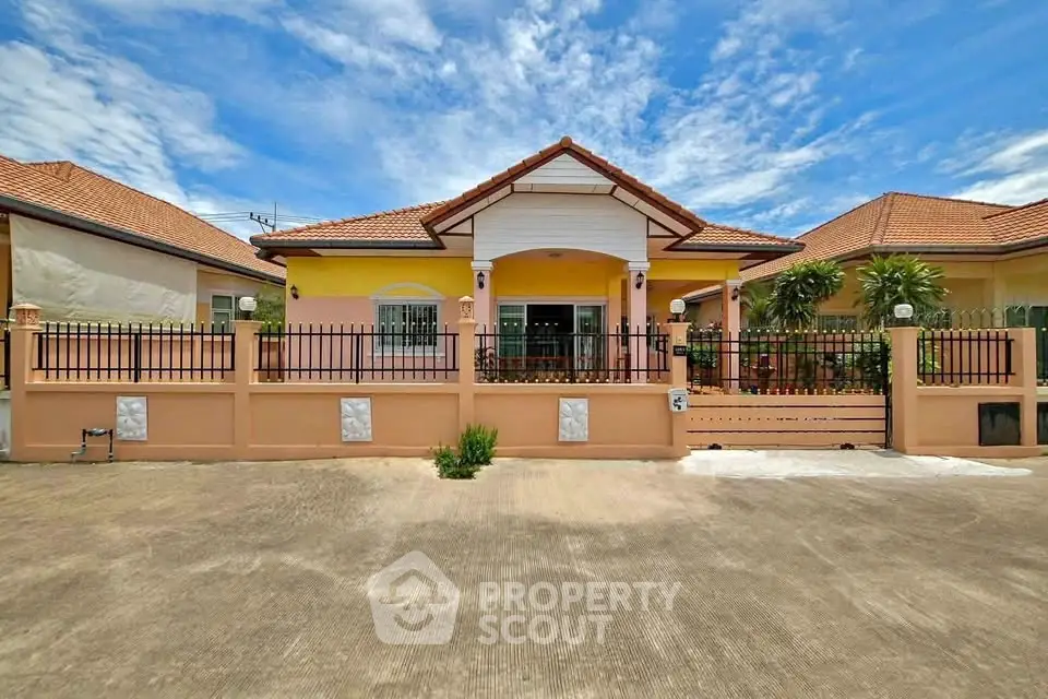 Charming single-story house with a fenced yard and tiled roof under a bright blue sky.
