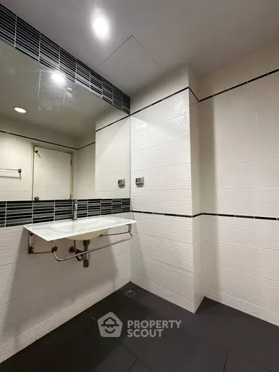 Modern minimalist bathroom with sleek white tiles and contemporary sink design.