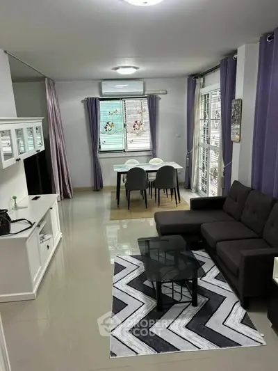 Modern living room with stylish decor and dining area, featuring sleek furniture and ample natural light.
