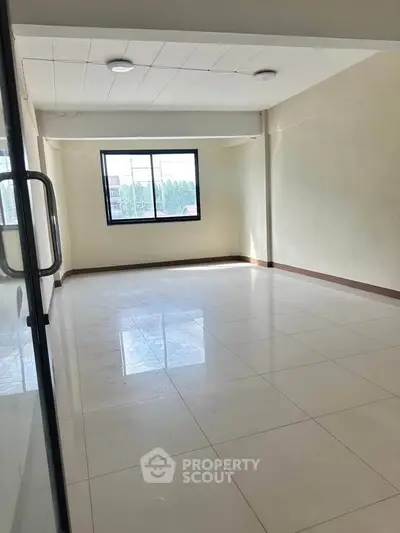 Spacious empty room with large window and glossy tiled floor, perfect for customization.