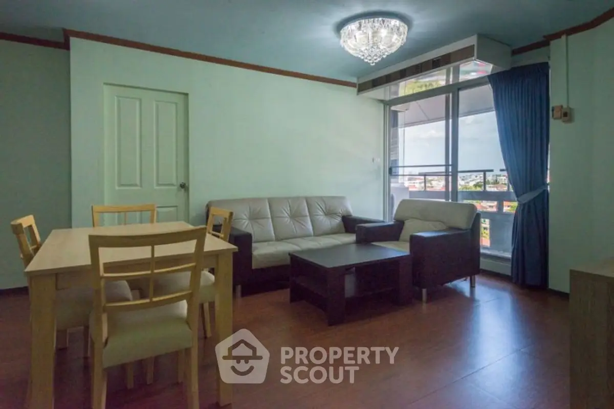 Spacious living room with modern furniture and large window offering city views.