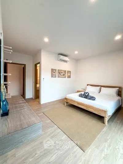 Spacious modern bedroom with wooden flooring and stylish decor