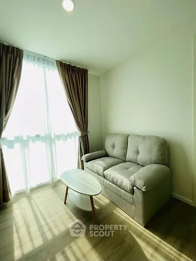 Bright living room with cozy sofa and natural light through large window, perfect for relaxation.