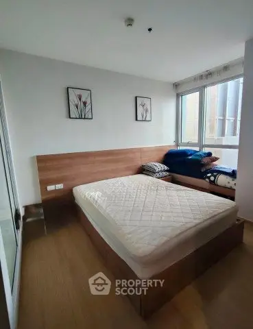 Cozy bedroom with wooden flooring and large window for natural light
