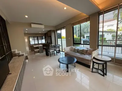 Spacious modern living room with open layout and large windows offering natural light and garden view.