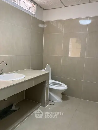 Modern bathroom with sleek beige tiles and contemporary fixtures.