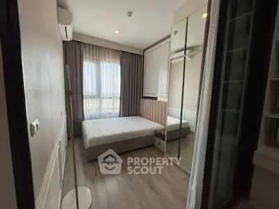 Modern bedroom with large window and mirrored wardrobe in stylish apartment.