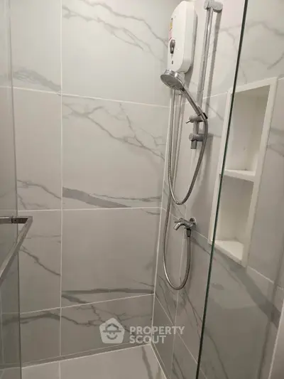 Modern bathroom with sleek marble tiles and a glass shower enclosure.