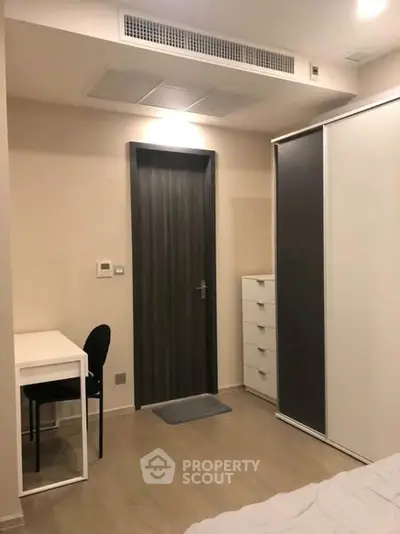 Modern bedroom with sleek furniture and minimalist design, featuring a desk and wardrobe.