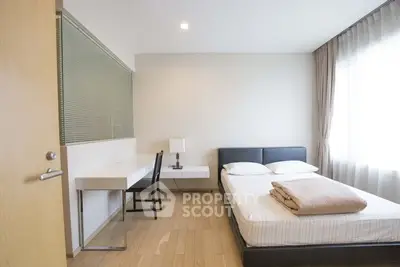 Modern minimalist bedroom with natural light and sleek furnishings.
