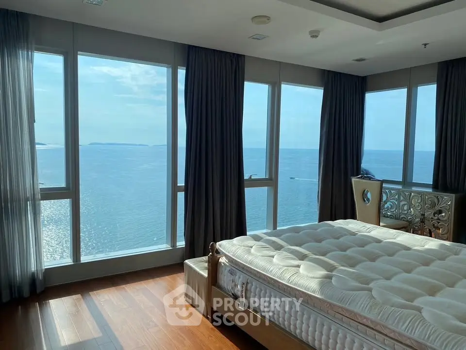 Luxurious bedroom with panoramic ocean view and floor-to-ceiling windows, offering serene and breathtaking scenery.