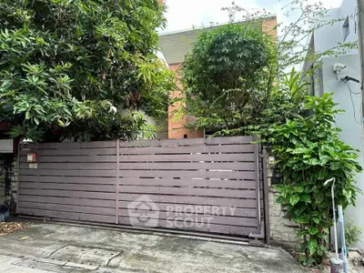 Charming residential property with lush greenery and secure wooden gate