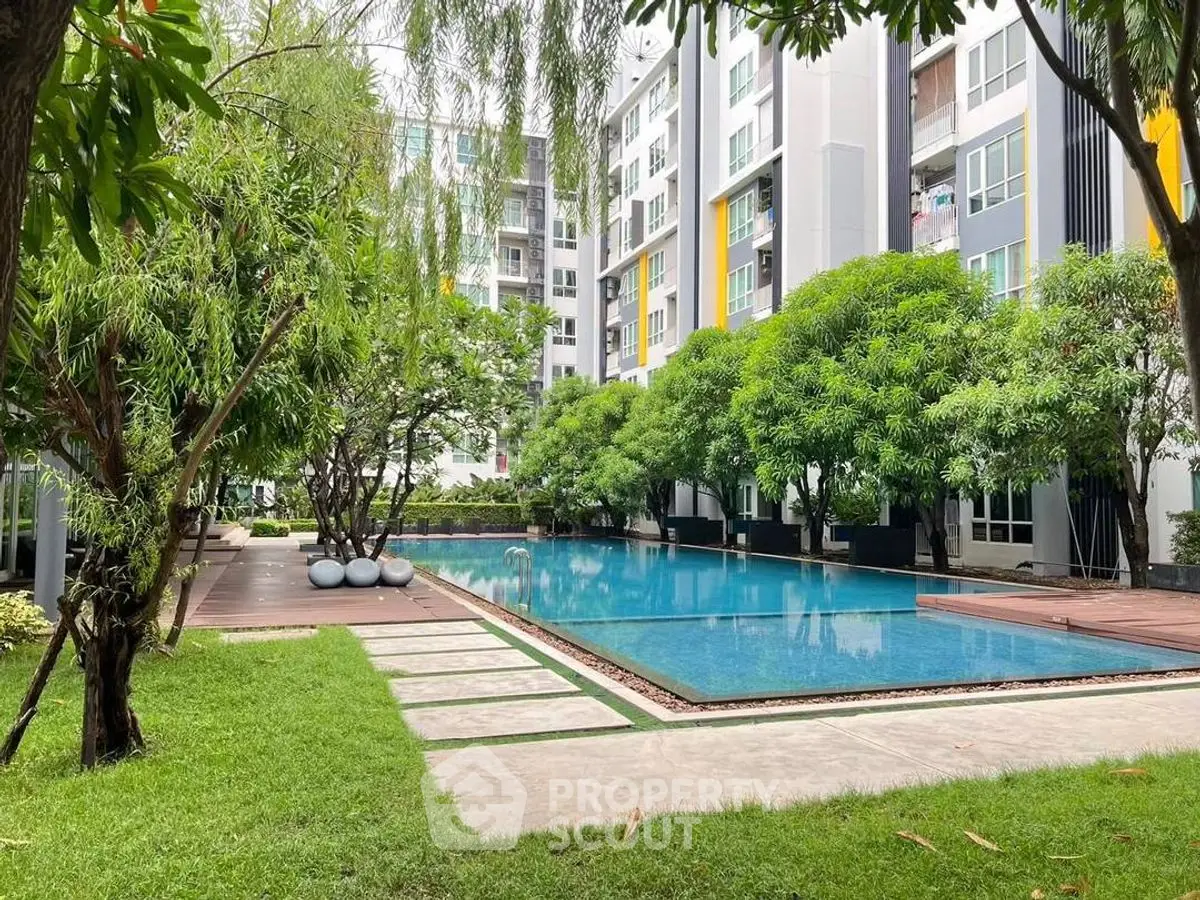 Modern apartment complex with lush garden and inviting swimming pool.