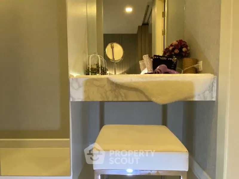 Elegant vanity area with marble countertop and plush stool in luxurious home.