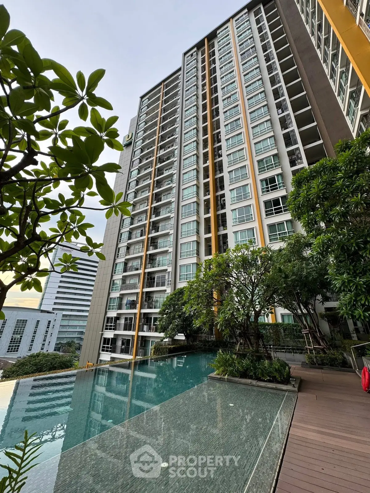 Modern high-rise building with luxurious pool and lush greenery