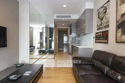 Modern living room with sleek kitchen, leather sofa, and stylish decor in a contemporary apartment.