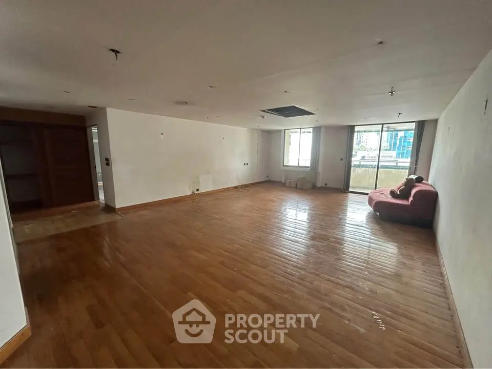 Spacious empty living room with hardwood floors and large windows.
