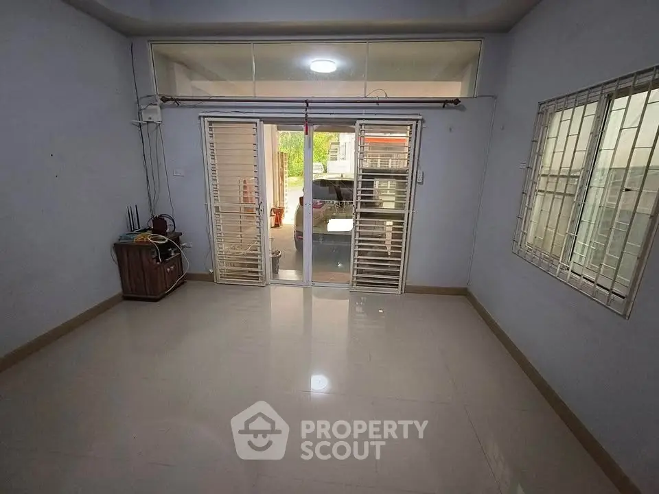 Spacious unfurnished room with large windows and sliding doors leading to a bright outdoor area.