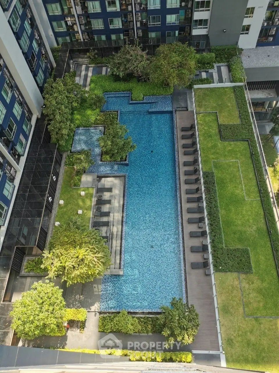 Stunning aerial view of modern apartment complex with luxurious swimming pool and lush green landscaping.