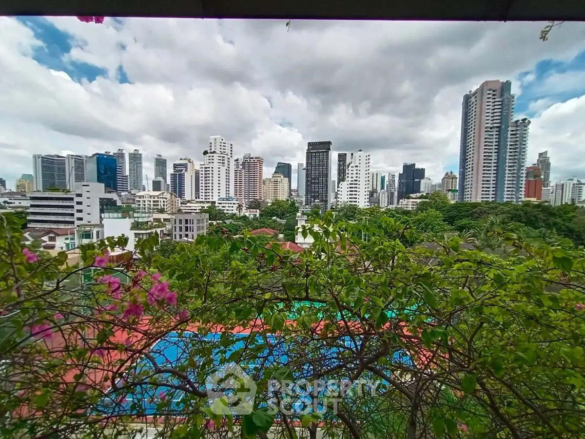 Stunning cityscape view from a high-rise balcony overlooking lush greenery and urban skyline.