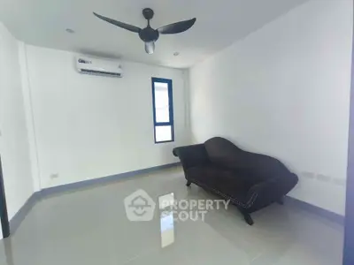 Minimalist living room with sleek black sofa and ceiling fan