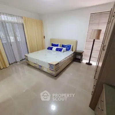 Spacious bedroom with modern furnishings and large windows for natural light.