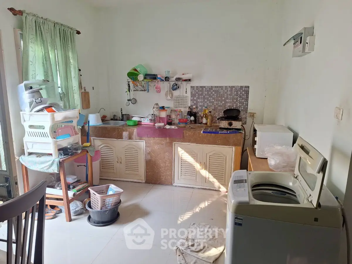 Cozy kitchen with washing machine and open layout, perfect for small apartments.