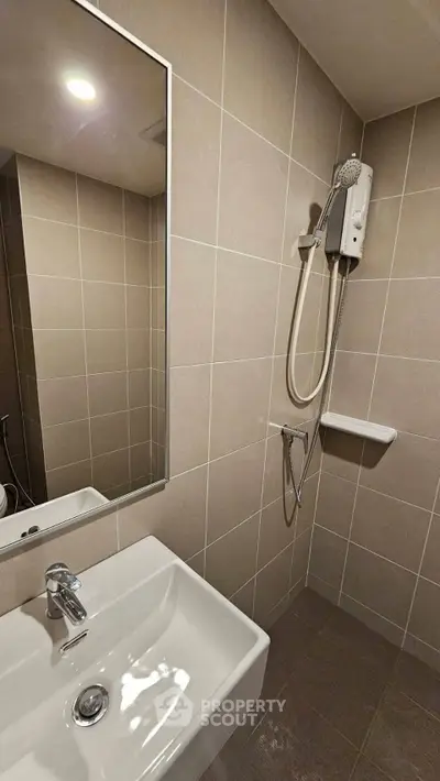 Modern bathroom with sleek tiles and a wall-mounted shower unit, perfect for urban living.