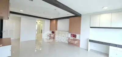 Spacious modern living room with sleek built-in cabinets and glossy tiled flooring.