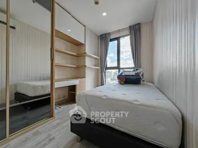 Modern bedroom with large window and built-in storage in a stylish apartment.