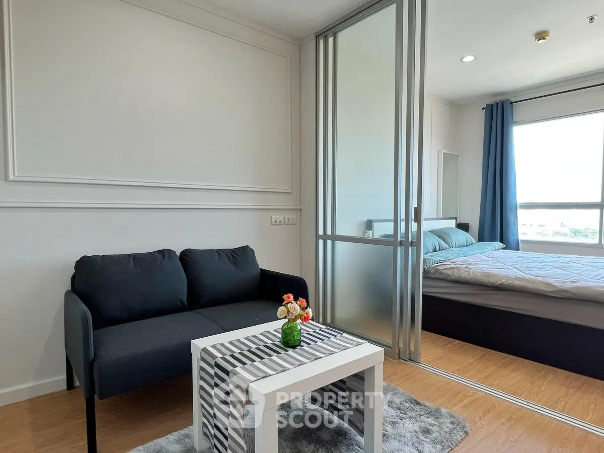 Modern apartment with cozy living room and bedroom separated by glass sliding doors, featuring stylish decor.