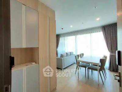 Spacious modern living room with dining area and large windows in a bright apartment.