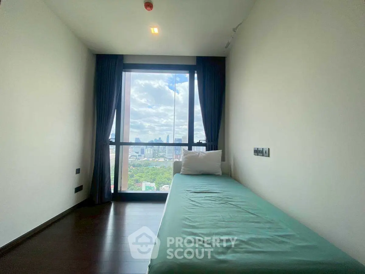 Cozy bedroom with city view and large window, perfect for urban living.