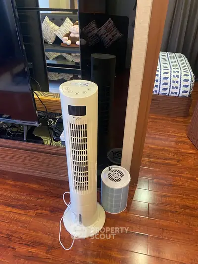 Modern living room with stylish wooden flooring and sleek tower fan for comfort.