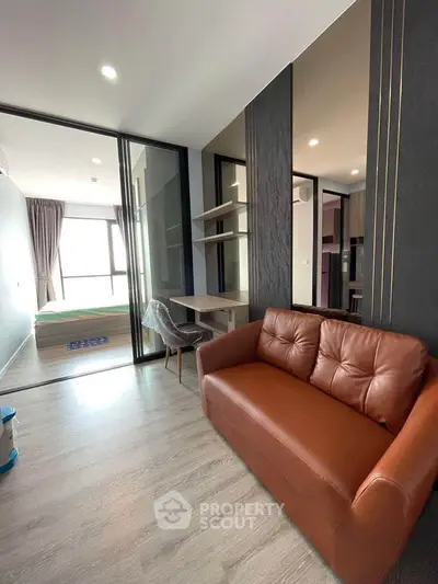 Modern apartment interior with stylish brown sofa and study area, featuring sleek design and natural light.