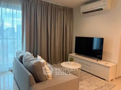 Modern living room with large TV, cozy sofa, and elegant curtains in a stylish apartment.