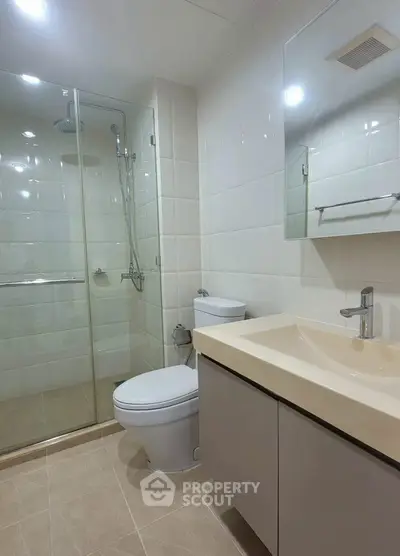 Modern bathroom with glass shower, sleek vanity, and neutral tiles