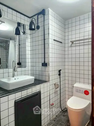 Modern bathroom with white tiles, sleek fixtures, and contemporary lighting.