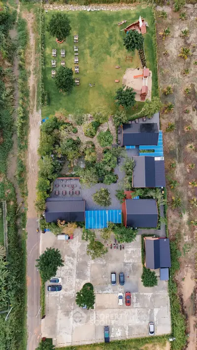 Aerial view of a spacious property with lush gardens and ample parking space.