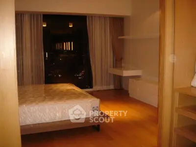 Spacious bedroom with large window offering stunning night views, featuring modern wooden flooring and minimalist design.