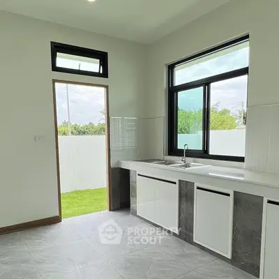Modern kitchen with sleek countertops and large windows overlooking a lush garden.