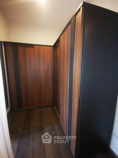 Spacious walk-in closet with elegant wooden finishes and ample storage space.